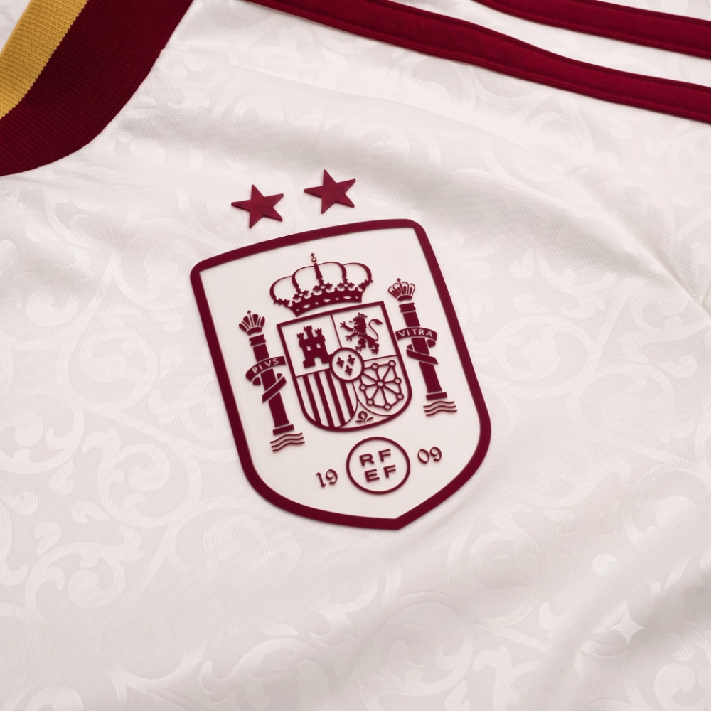 Equipación Visitante Niño España 2026 2 Detalle de la camiseta visitante de España 2026 para adulto, con el escudo bordado y las dos estrellas de campeón del mundo.